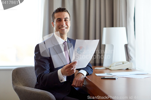 Image of businessman with papers working at hotel room