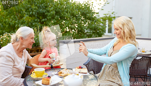 Image of woman photographing her family at cafe