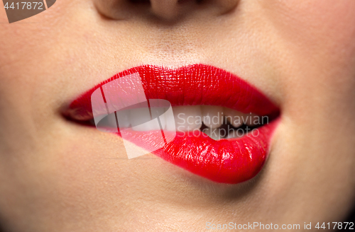 Image of close up of woman with red lipstick biting lip