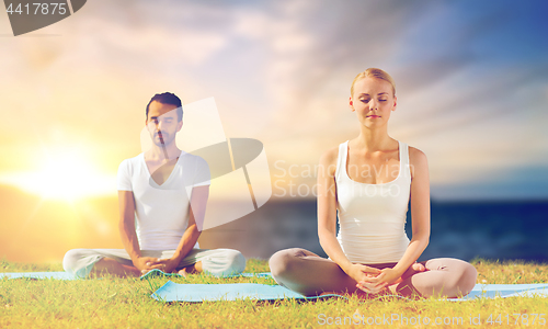 Image of happy couple making yoga and meditating outdoors