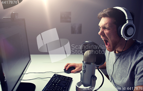 Image of man in headset playing computer video game at home