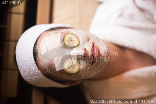 Image of woman is getting facial clay mask at spa