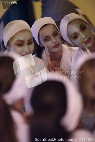Image of women putting face masks in the bathroom