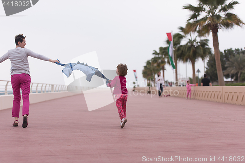 Image of mother and cute little girl on the promenade by the sea