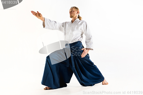 Image of Aikido master practices defense posture. Healthy lifestyle and sports concept. Man with beard in white kimono on white background.