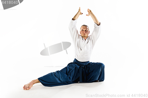 Image of Aikido master practices defense posture. Healthy lifestyle and sports concept. Man with beard in white kimono on white background.