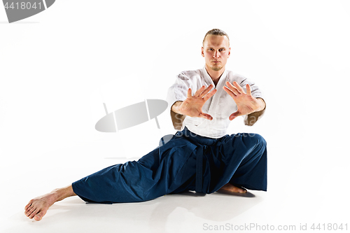 Image of Aikido master practices defense posture. Healthy lifestyle and sports concept. Man with beard in white kimono on white background.