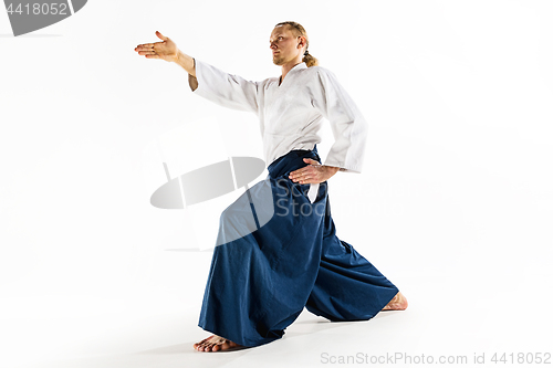 Image of Aikido master practices defense posture. Healthy lifestyle and sports concept. Man with beard in white kimono on white background.