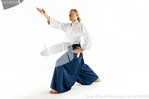 Image of Aikido master practices defense posture. Healthy lifestyle and sports concept. Man with beard in white kimono on white background.