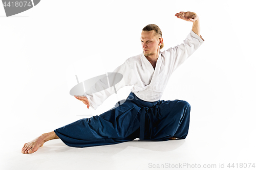 Image of Aikido master practices defense posture. Healthy lifestyle and sports concept. Man with beard in white kimono on white background.