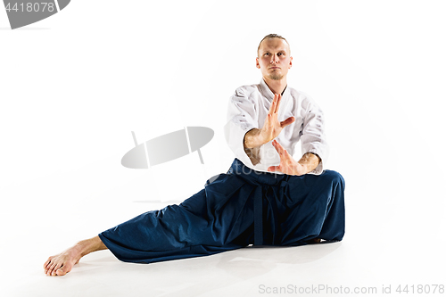 Image of Aikido master practices defense posture. Healthy lifestyle and sports concept. Man with beard in white kimono on white background.