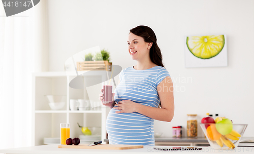 Image of happy pregnant woman drinking juice at home
