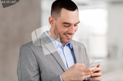 Image of smiling businessman with smarphone at office