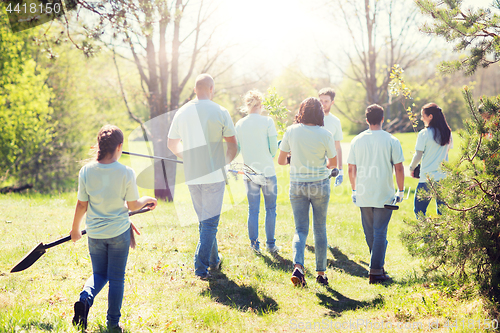 Image of happy volunteers with seedlings and garden tools