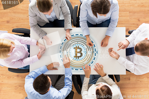 Image of business team at table with bitcoin icon