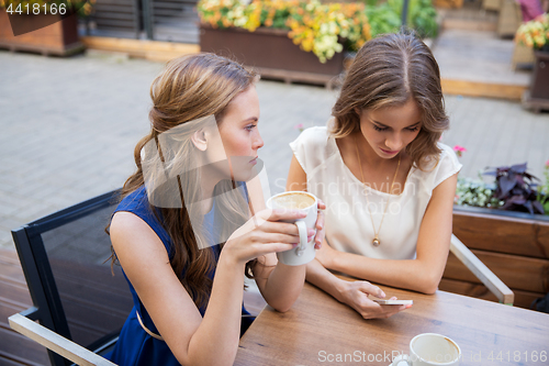 Image of young women with smartphone and coffee at cafe