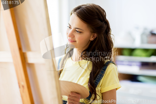 Image of student girl with easel painting at art school