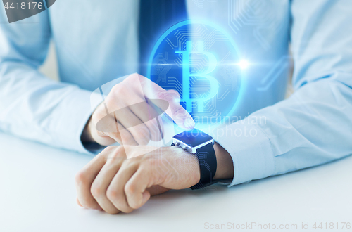 Image of close up of hands with bitcoin on smart watch
