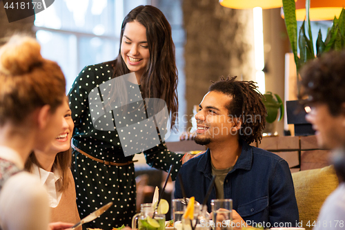 Image of happy friends eating at restaurant