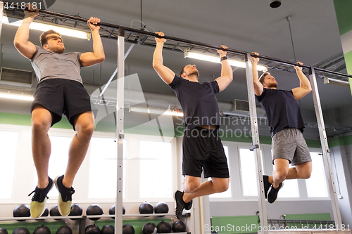 Image of group of young men doing pull-ups in gym