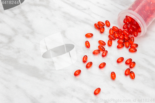 Image of Bottle with red shiny pills on marble background