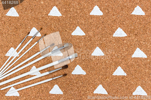 Image of Paintbrushes on cork background with painted triangles