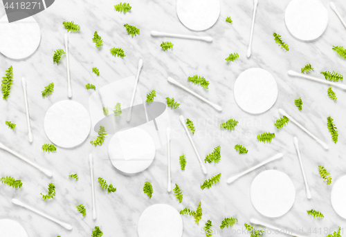 Image of Cotton pads, swabs and green leaves on marble background