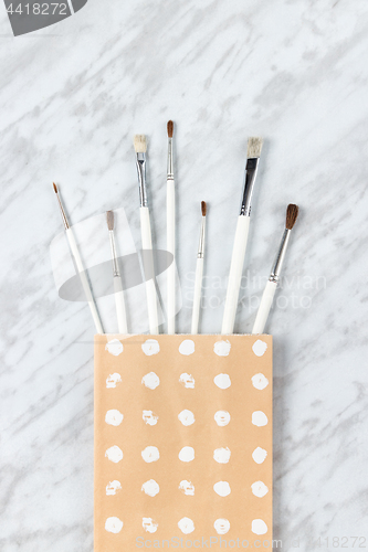 Image of White paint brushes in a decorative paper bag