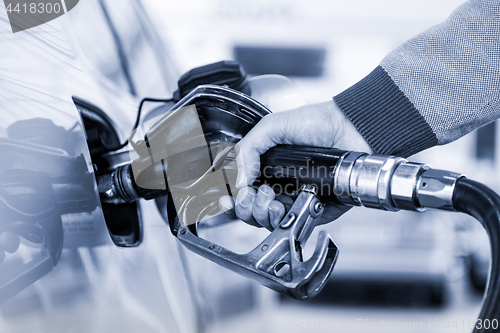 Image of Closeup of mans hand pumping gasoline fuel in car at gas station.