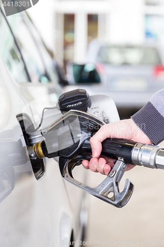 Image of Closeup of mans hand pumping gasoline fuel in car at gas station.