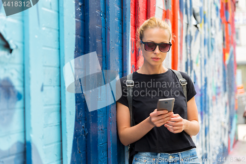 Image of Woman using smartphone against colorful graffiti wall in New York city, USA.