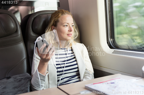 Image of Businesswoman communicating on mobile phone while traveling by train.