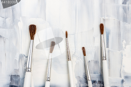 Image of New paint brushes on black and white canvas