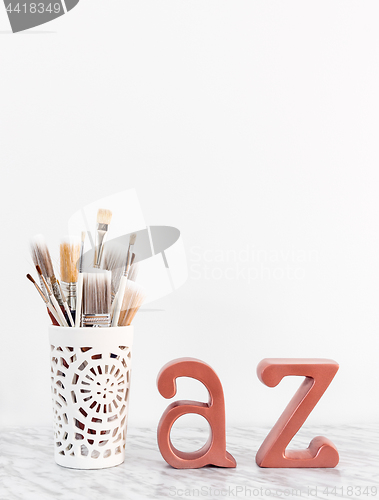 Image of Paintbrushes with metal A and Z letters on marble surface