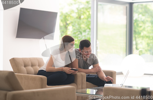 Image of couple relaxing at  home with tablet and laptop computers
