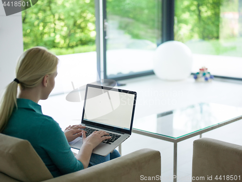 Image of Young woman using laptop at home