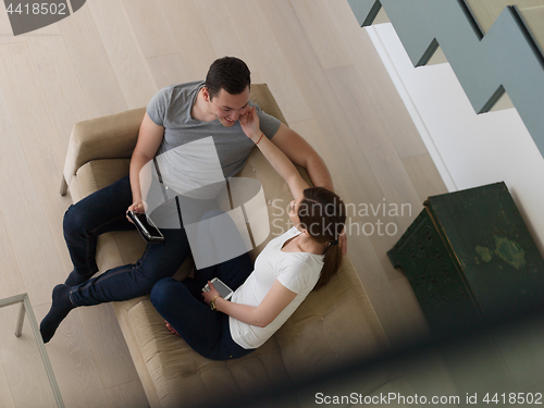 Image of couple relaxing at  home with tablet computers