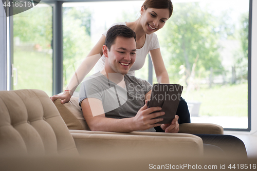 Image of couple relaxing at  home with tablet computers