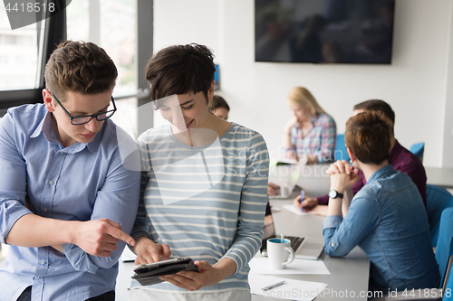 Image of Two Business People Working With Tablet in office