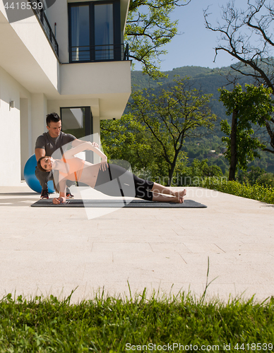 Image of woman with personal trainer doing morning yoga exercises