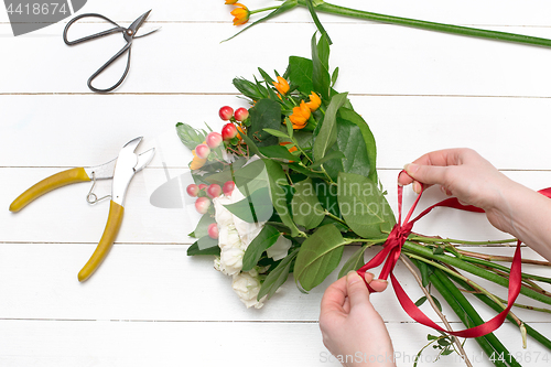 Image of Female florist making beautiful bouquet at flower shop