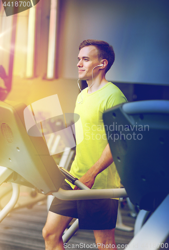 Image of man with smartphone exercising on treadmill in gym