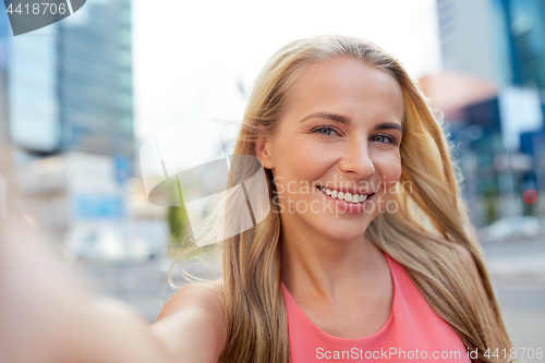 Image of happy young woman taking selfie on city street