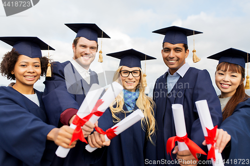 Image of happy students in mortar boards with diplomas