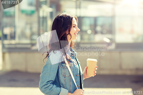 Image of happy young woman drinking coffee on city street