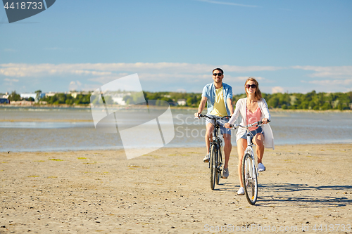 Image of happy young couple riding bicycles at seaside