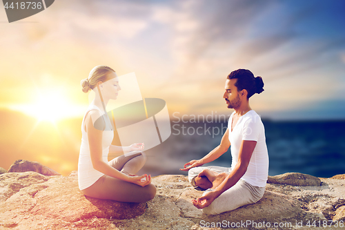 Image of happy couple making yoga and meditating outdoors