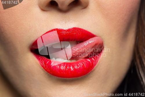 Image of close up of woman with red lipstick licking lips