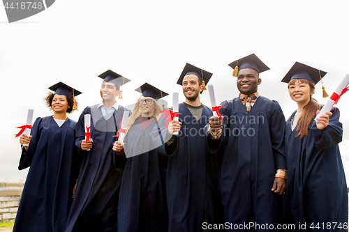 Image of happy students in mortar boards with diplomas