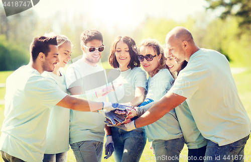 Image of group of volunteers putting hands on top in park